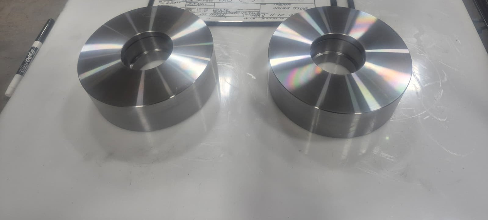 Machined and fabricated aluminum components beside an engineering drawing