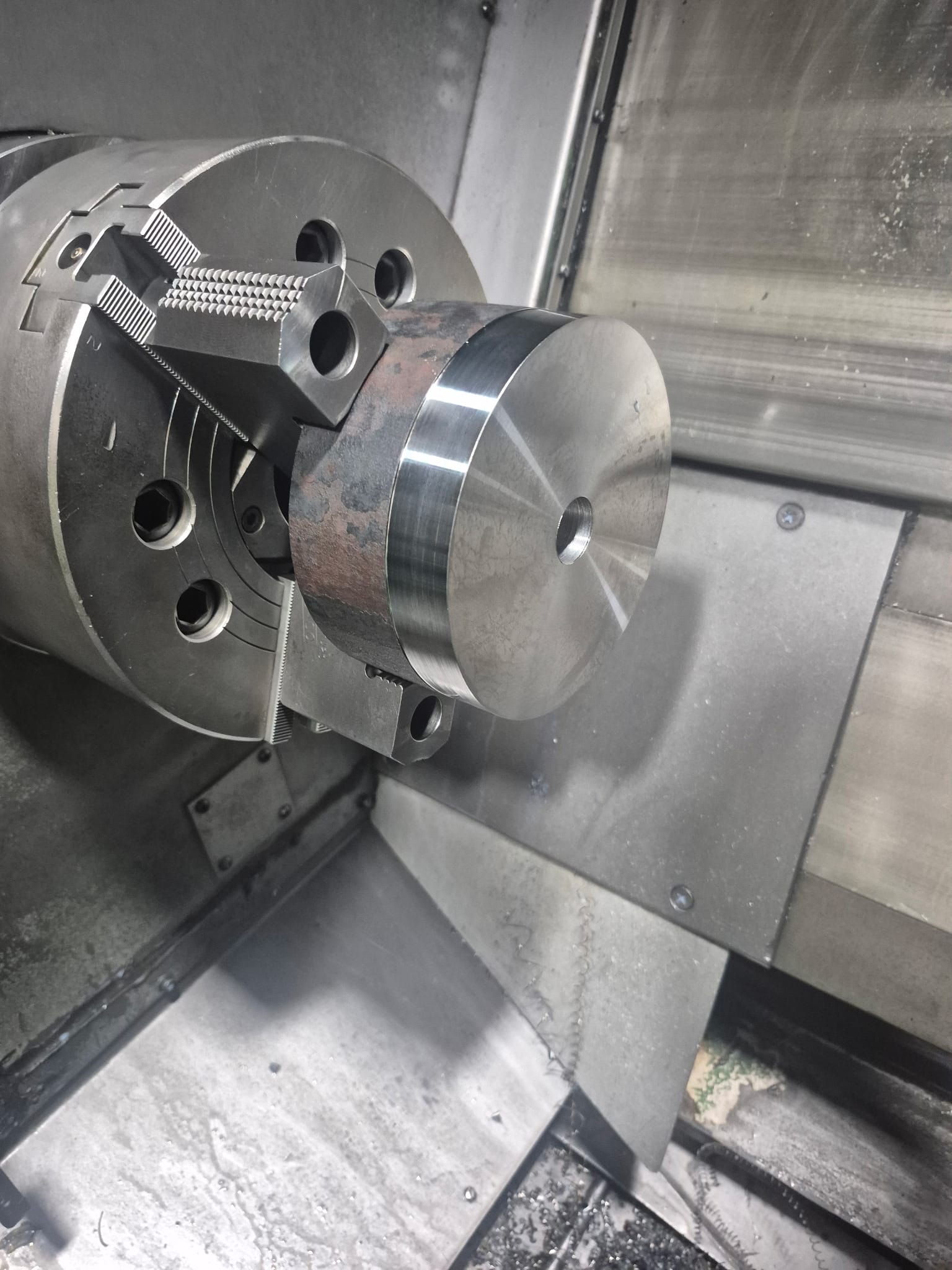 Finished precision-turned steel component in a lathe chuck