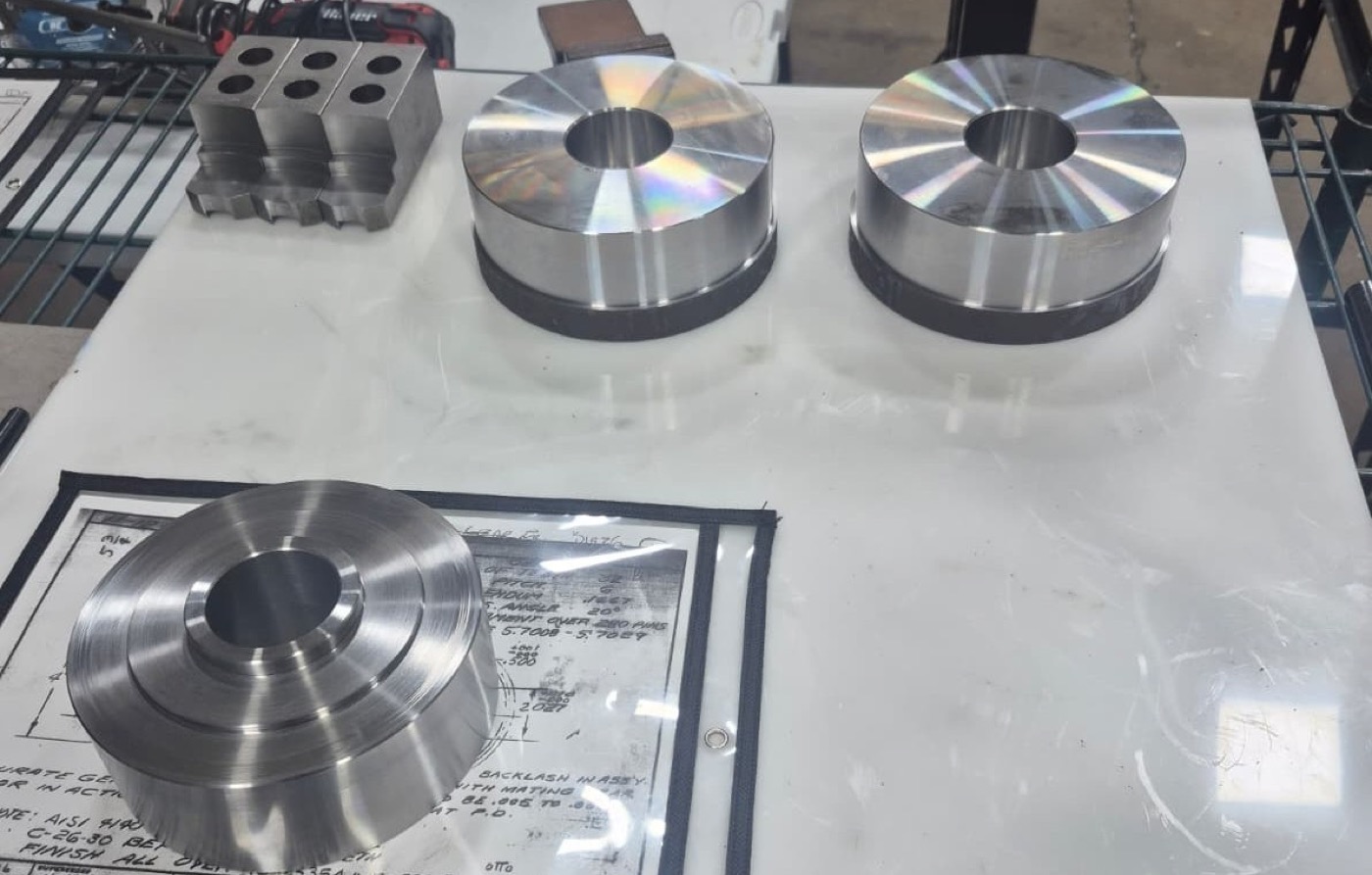 Turned gear blanks and hubs beside an engineering drawing