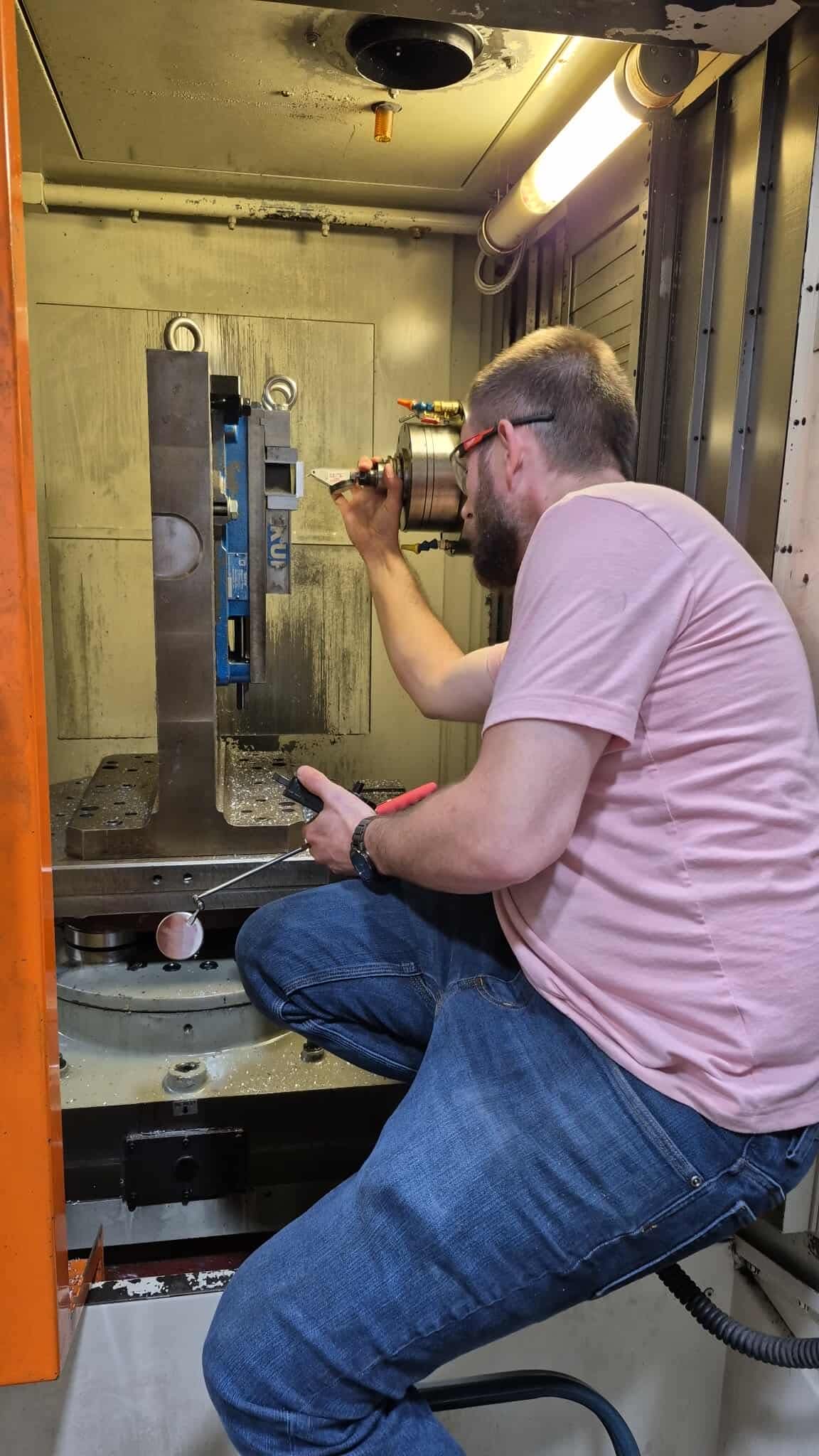 Machinist indicating a fixture inside the horizontal machining center