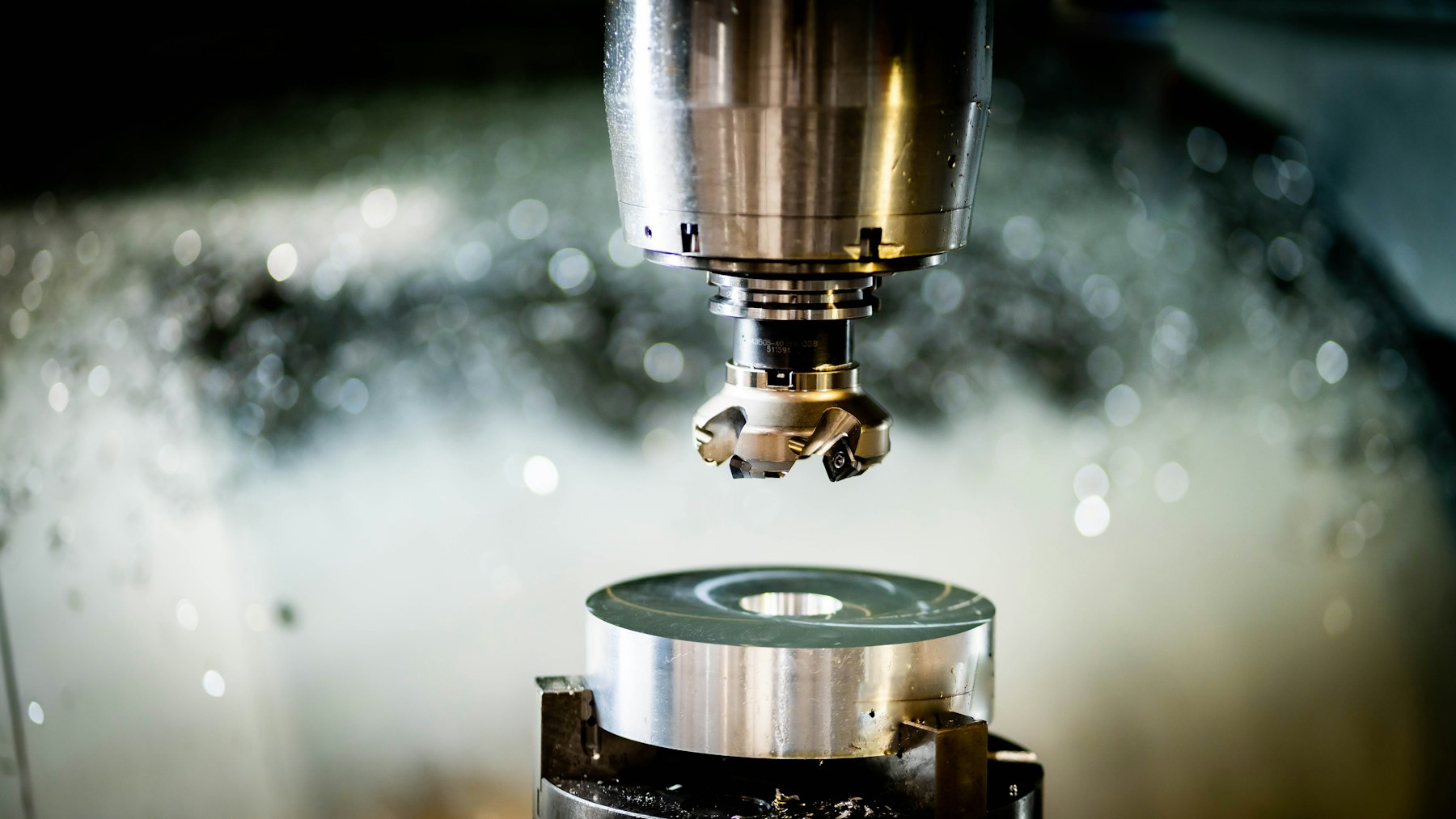 Face mill cutting a round steel workpiece under flood coolant on a CNC machining center