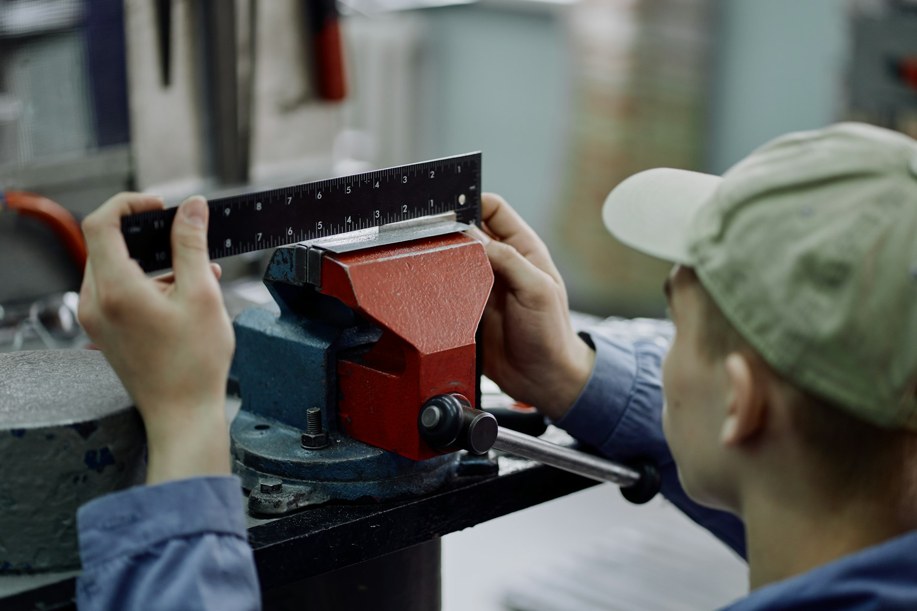 Machinist measuring a workpiece clamped in a bench vise with a steel rule