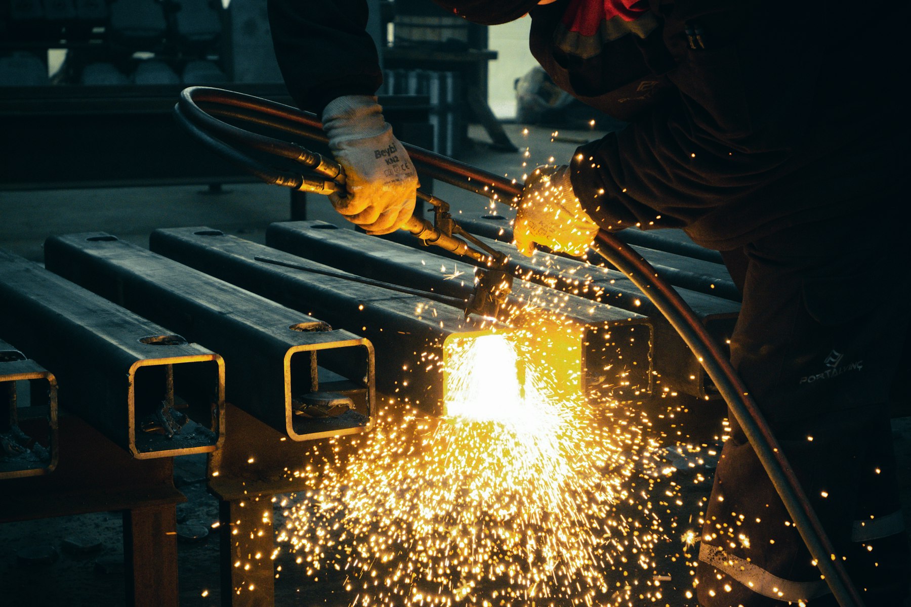 Fabricator welding square steel tubing on a workbench